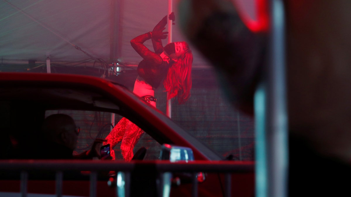 An exotic dancer wears personal protective equipment while performing in a drive-through go-go dance tent offered by the Lucky Devil Lounge strip club in Portland