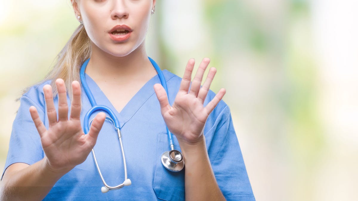 Young blonde surgeon doctor woman over isolated background afraid and terrified with fear expression stop gesture with hands, shouting in shock. Panic concept.