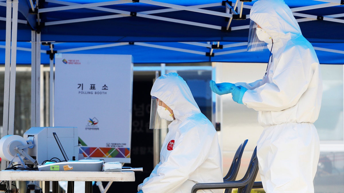 Election officials wearing protective gears, wait for voters during an early voting for the April 15 general elections at a special polling station set up for coronavirus patients and medical members at a treatment center in Yongin, South Korea.