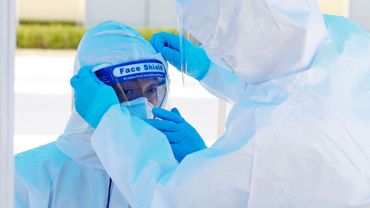 Election officials check their protective gears as they wait for voters during an early voting of the April 15 general elections at a special polling station set up for coronavirus patients and medical members at a treatment center in Yongin, South Korea.