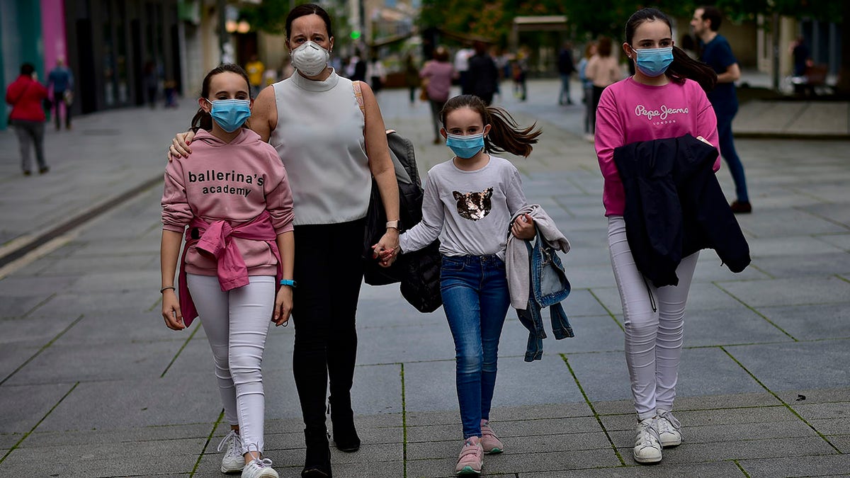 A family wearing face masks to protect of the coronavirus go for a walk at Carlos III promenade, in Pamplona, northern Spain, on Sunday. (AP Photo/Alvaro Barrientos)