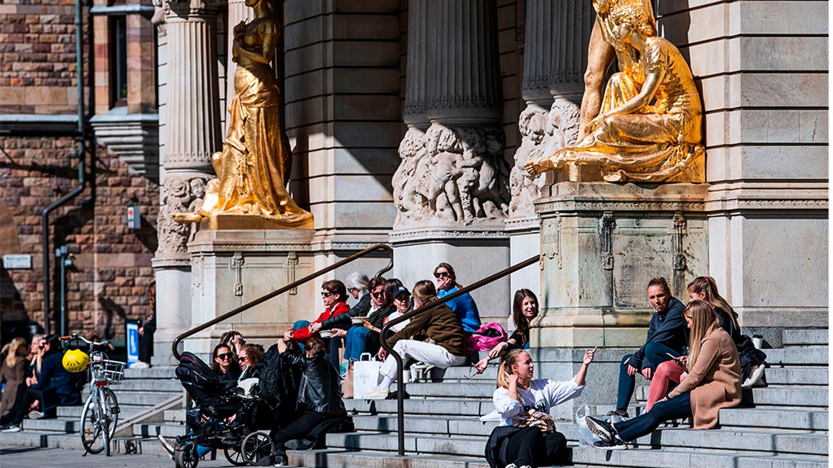 People sit and enjoy the spring weather outside the Royal Dramatic Theatre in Stockholm on April 15, 2020, during the coronavirus COVID-19 pandemic. (Photo by Jonathan NACKSTRAND / AFP) (Photo by JONATHAN NACKSTRAND/AFP via Getty Images)