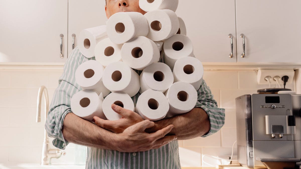 Man hoarding toilet paper holding many rolls