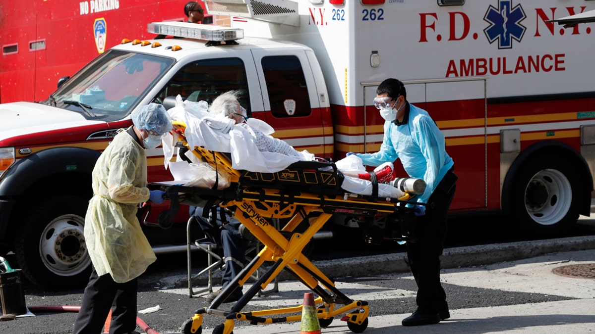 A patient is transferred from Elmhurst Hospital Center to a waiting ambulance during the current coronavirus outbreak, Tuesday, April 7, 2020, in New York. New York Gov. Andrew Cuomo said last week that the city's overtaxed hospitals could move patients to other medical facilities to ease the burden on local hospitals. (AP Photo/Kathy Willens)