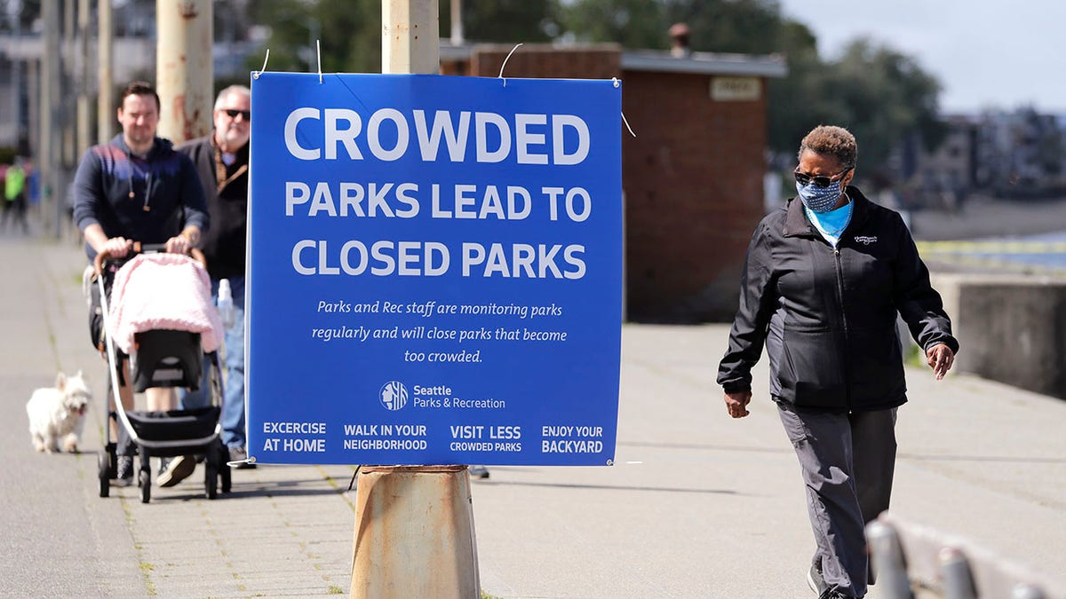 City guidelines for Seattle parks ask that people stay at least 6 feet apart, not to congregate and to keep moving to help prevent spread of the coronavirus. (AP Photo/Elaine Thompson)