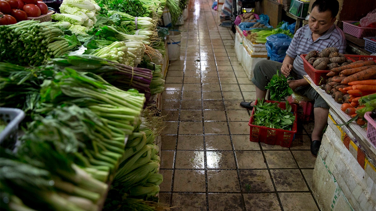 A vendor prepares vegetables for sale at a wet market in Shenzhen, China. (AP Photo/Ng Han Guan)