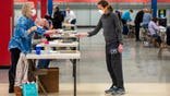 Bridget McDonald, right, receives a ballot from poll worker Patty Piek-Groth on Tuesday, April 7, 2020, at the Janesville Mall in Janesville, Wis. Hundreds of voters in Wisconsin are waiting in line to cast ballots at polling places for the state's presidential primary election, ignoring a stay-at-home order over the coronavirus threat. (Angela Major/The Janesville Gazette via AP)