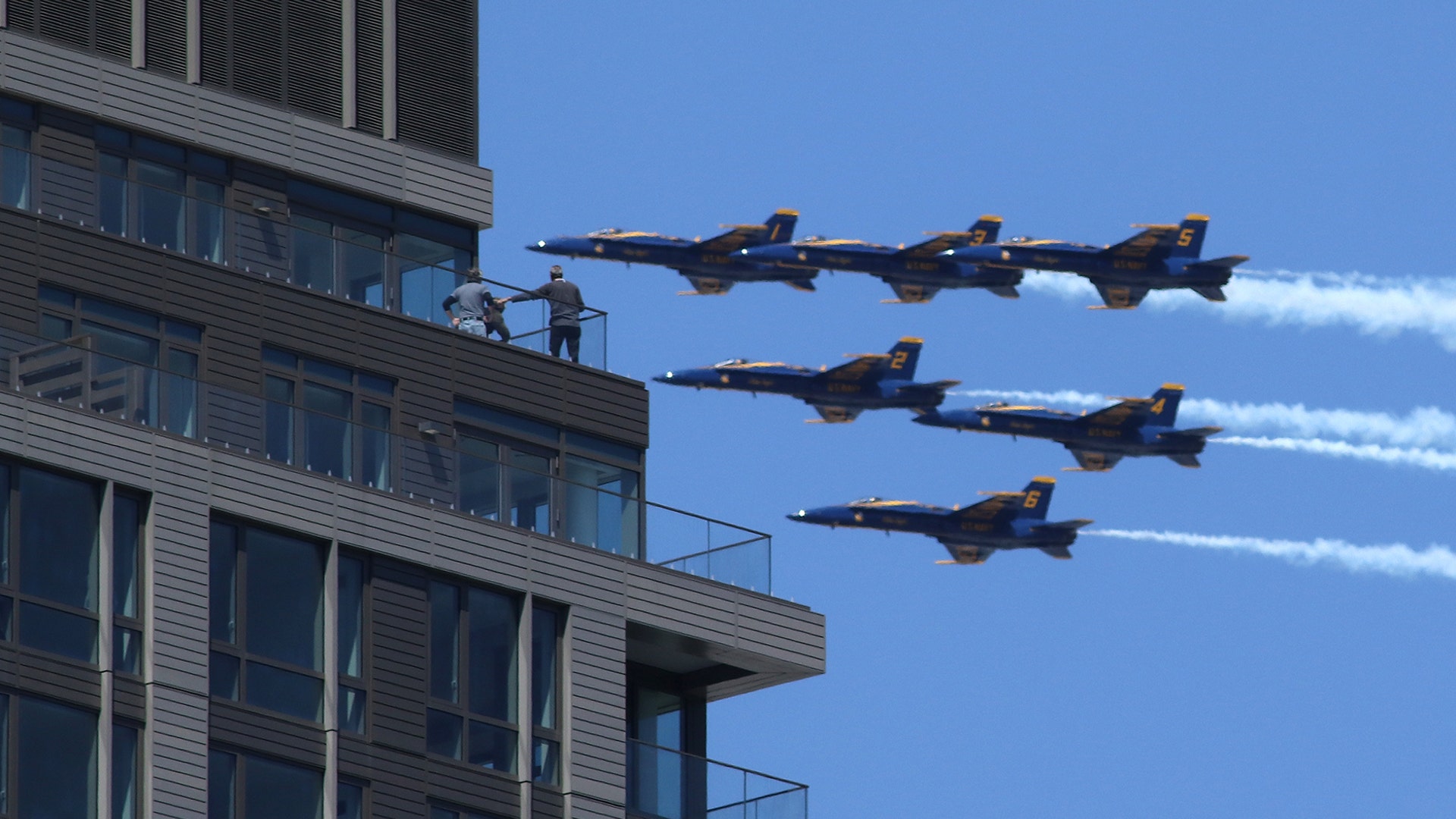 People watch as the U.S. Navy's Blue Angels fly past an apartment building as they perform a flyover tribute over New Jersey and New York City to honor COVID-19 front-line workers in Jersey City, New Jersey April 28, 2020. 