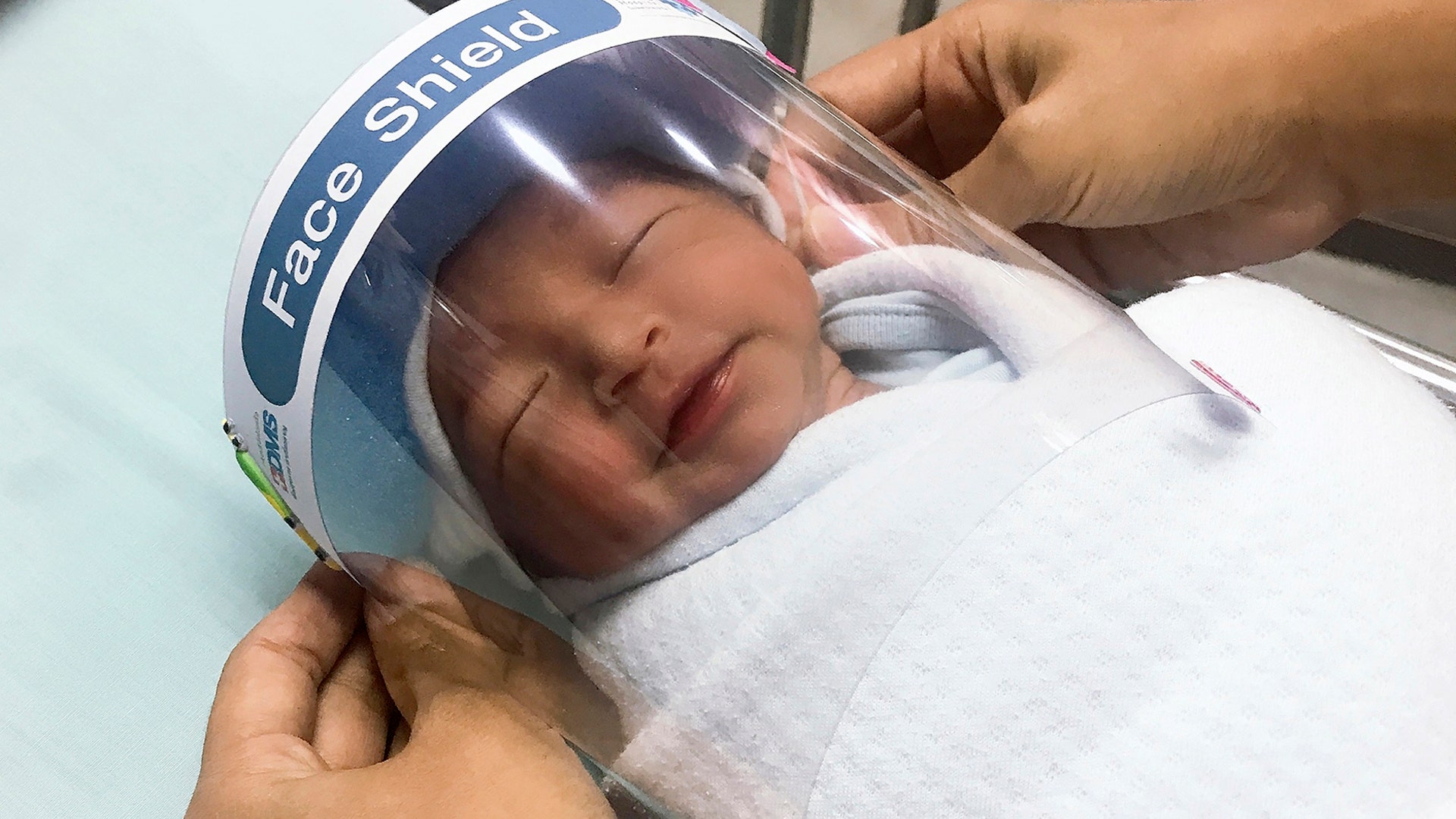 A nurse adjusts a tiny face shield for a newborn baby to protect him from coronavirus at the newborn nursery a hospital in Samutprakarn province, Thailand, April 4, 2020.