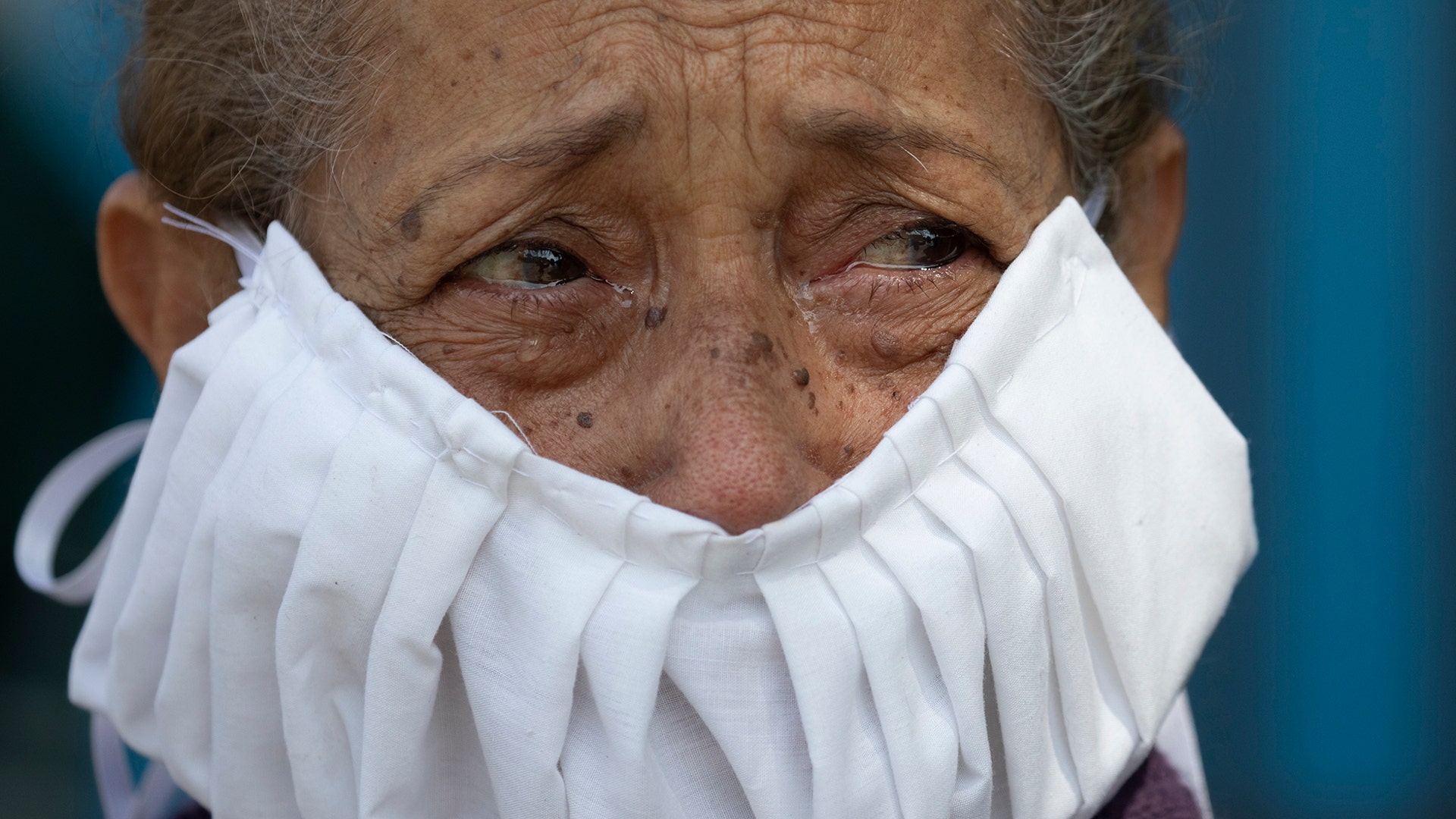 With tears on her eyes and wearing a homemade face mask, a devotee of the "Nazareno de San Pablo" watches a statue of Jesus transported in a Popemobile during Holy Week celebrations in Caracas, Venezuela, April 8, 2020.