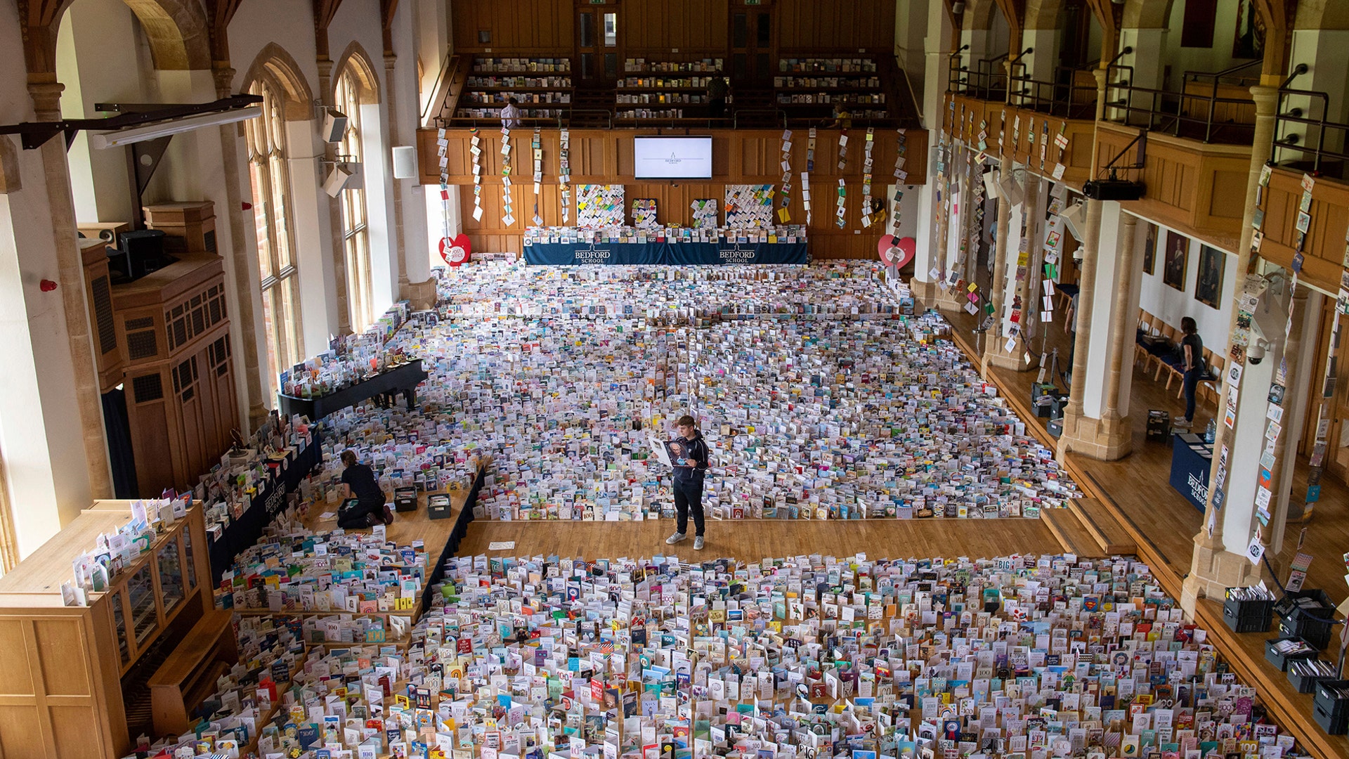 One-hundred-year-old World War II veteran Captain Tom Moore's grandson, Benjie, stands in the Great Hall of Bedford School where over 120,000 birthday cards sent from around the world are being opened and displayed by staff after he completed his quest to walk 100 laps of his garden. Moore raised almost $38 million for Britain’s National Health Service, in Bedfordshire, England, April 27, 2020. 