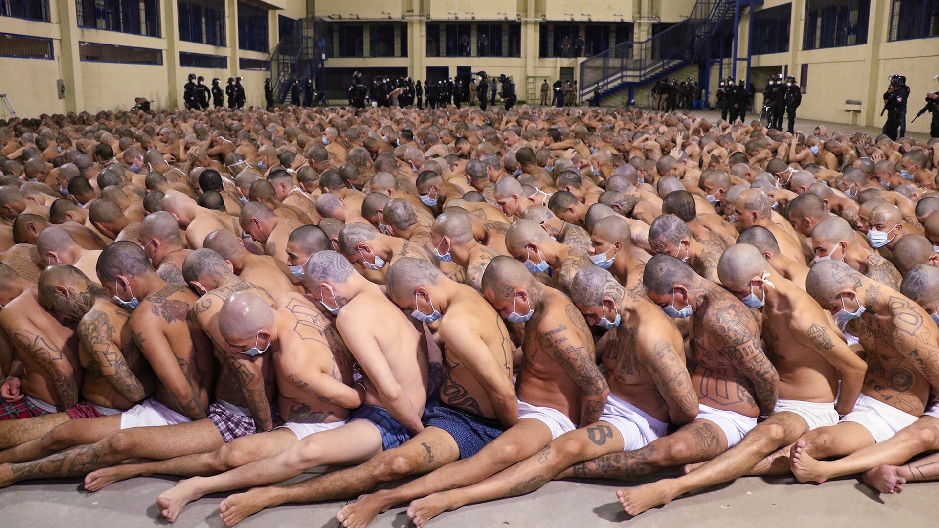 Police wearing masks as precautions against the coronavirus guard inmates also wearing masks, during a security operation after President Nayib Bukele decreed a maximum emergency in prisons housing gang members at the Izalco prison in San Salvador, El Salvador, April 25, 2020. 