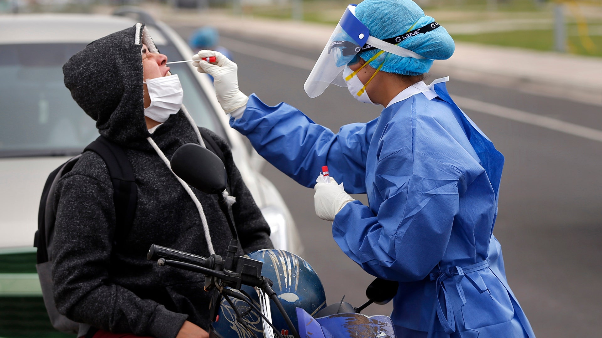 A nurse from the Ministry of Public Health takes a sample from a person on a motorcycle, at a coronavirus mobile test site in Asuncion, Paraguay, April 8, 2020.