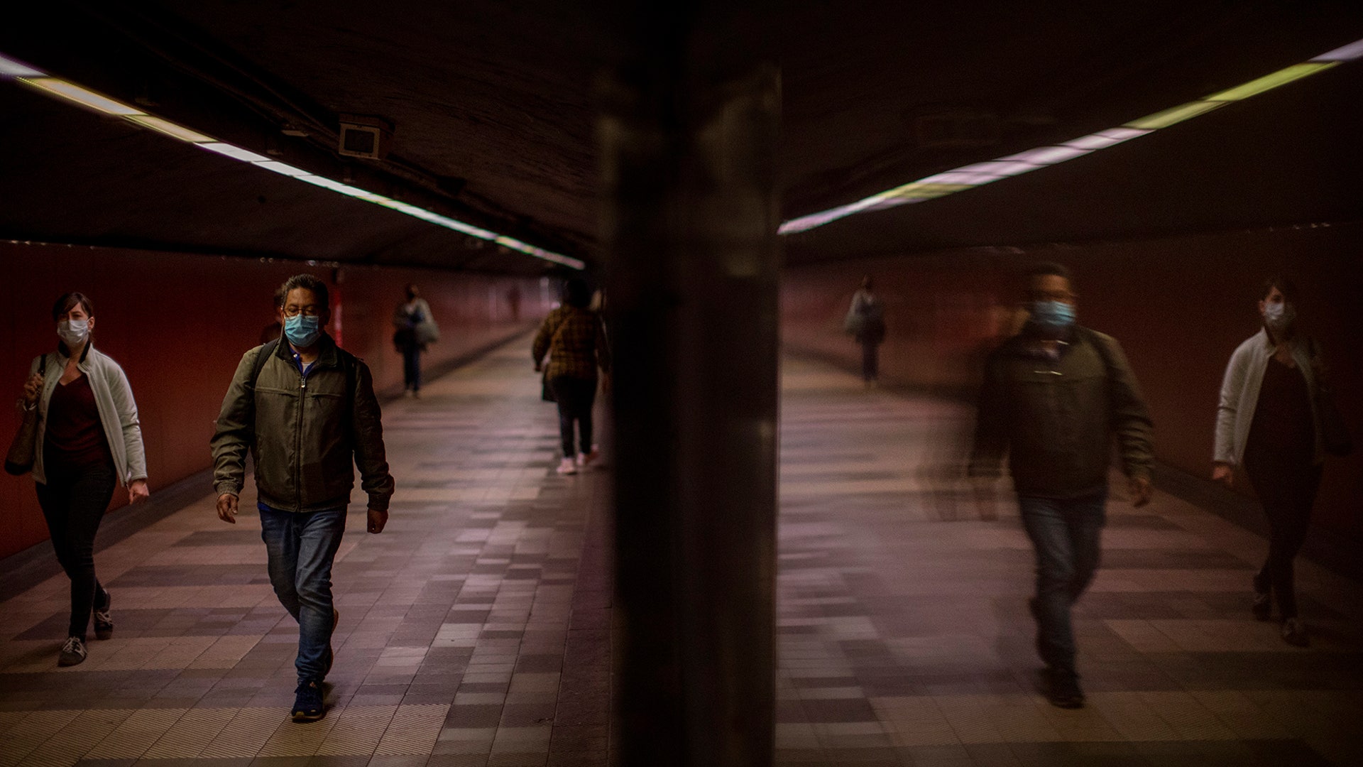 Passengers wearing face masks to prevent the spread of coronavirus, walk along a tunnel connecting platforms in a metro station in Barcelona, Spain, April 15, 2020. 