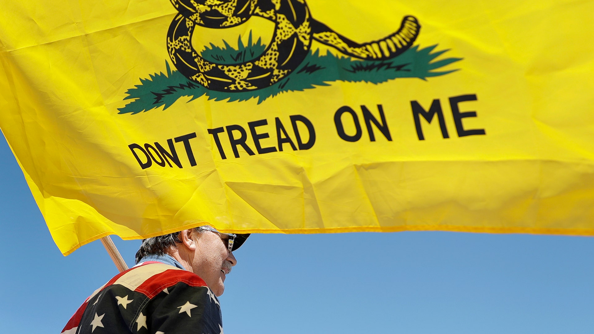 A man holds a flag as he attends a rally to protest stay-at-home orders put into place due to the COVID-19 outbreak outside the Missouri Capitol in Jefferson City, Missouri, April 21, 2020.  