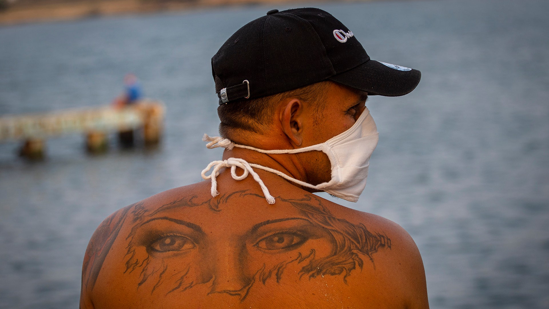 A man wearing a mask as a precaution against the spread of the new coronavirus spends the afternoon sitting by the sea in Cojimar, Cuba, April 14, 2020. 