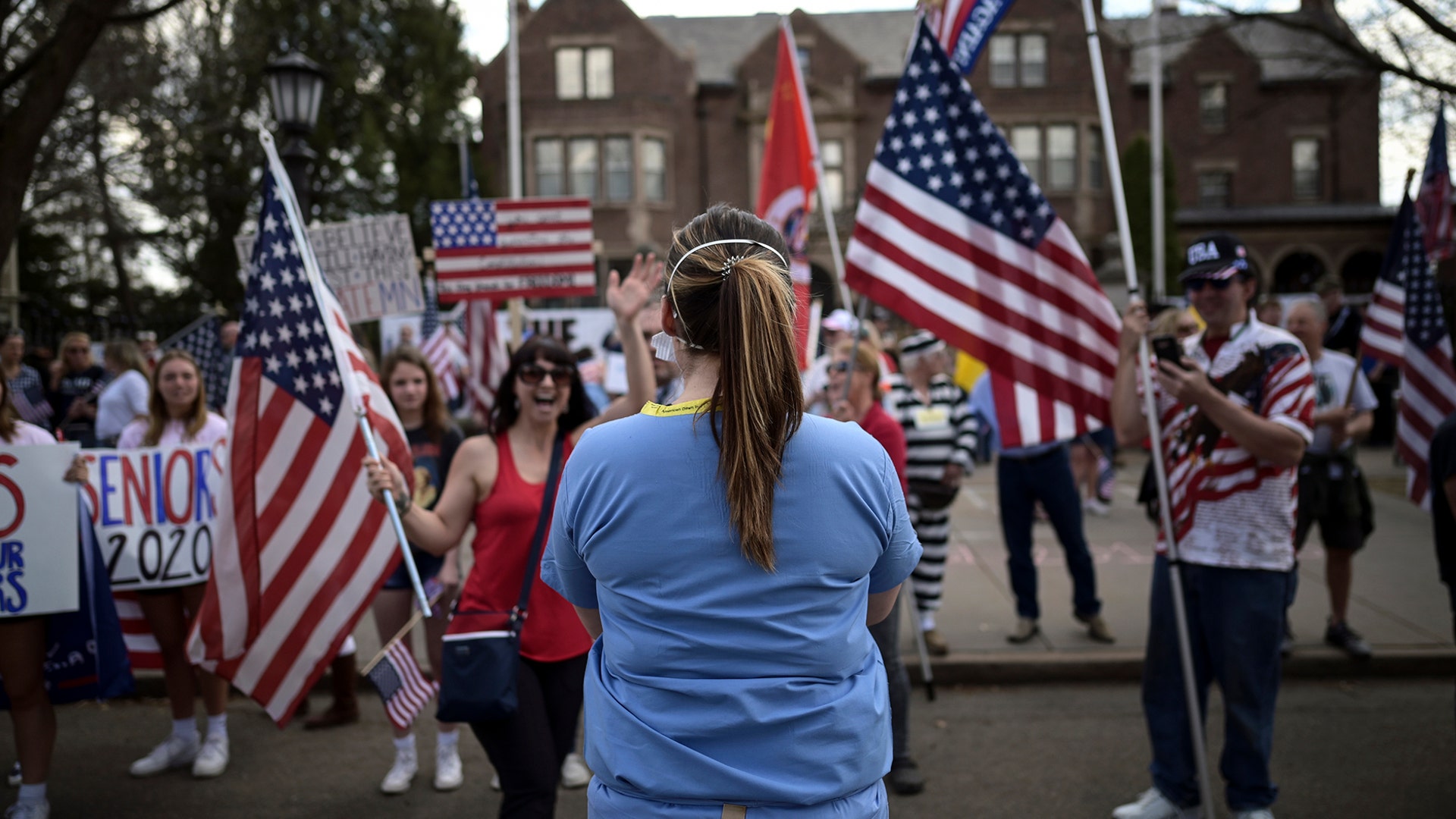 A woman who identified herself as a registered nurse in a local emergency room counterprotests in front of a demonstration to open up the state from the restrictions in place due to the new coronavirus, organized by the 3% United Patriots group, outside the Governor's Mansion, in St. Paul, Minnesota, April 25, 2020.