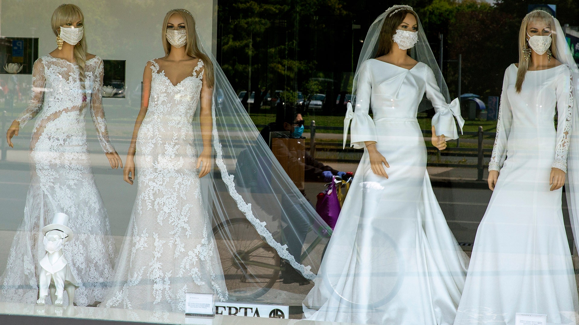 A cyclist wearing a protective mask to protect against coronavirus is reflected in the window of a wedding dress store with mannequins wearing face masks, in Zagreb, Croatia, April 23, 2020. 