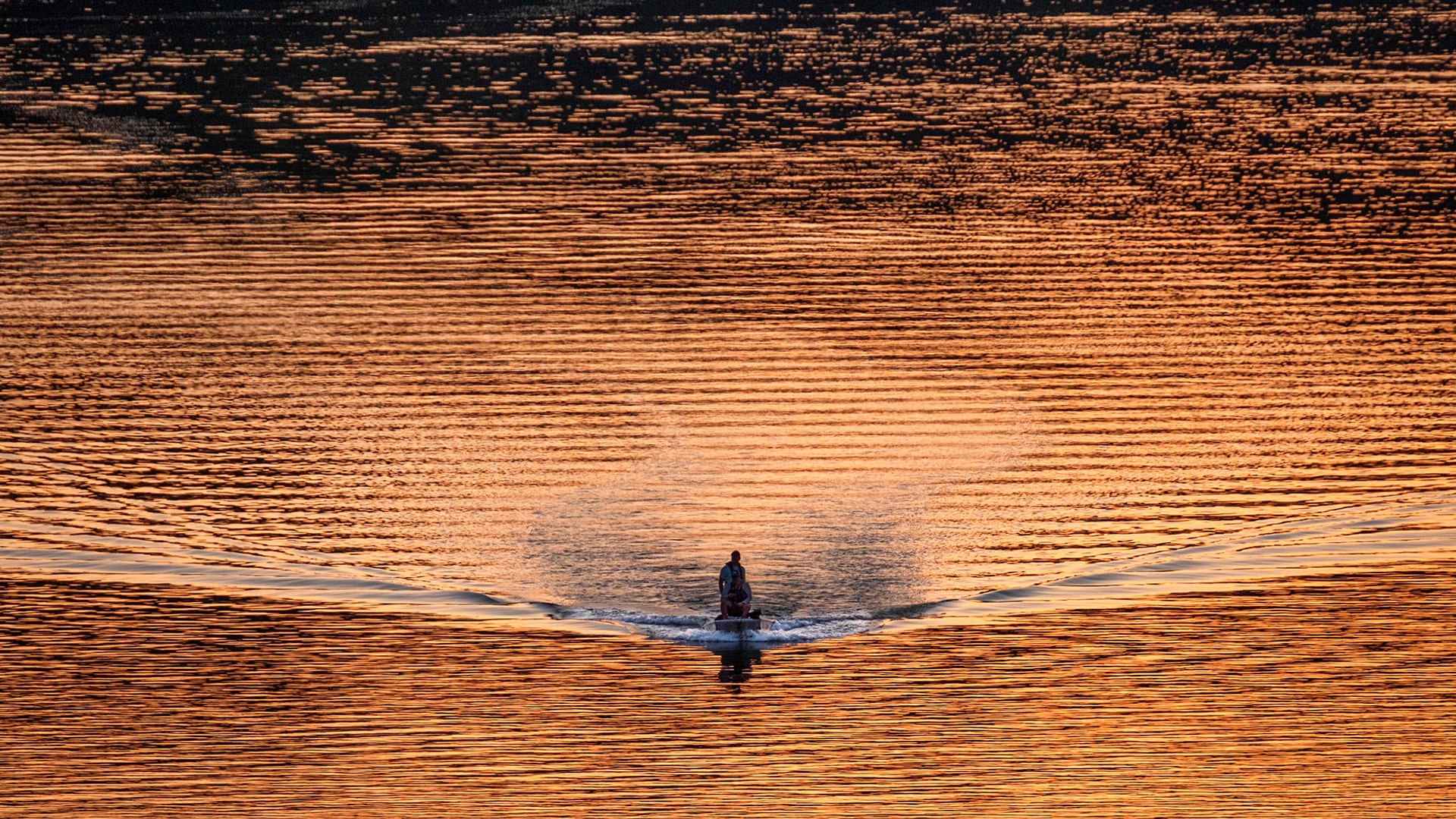 A single bass fishing boat cruises along the Potomac River at sunset in Washington, April 8, 2020.