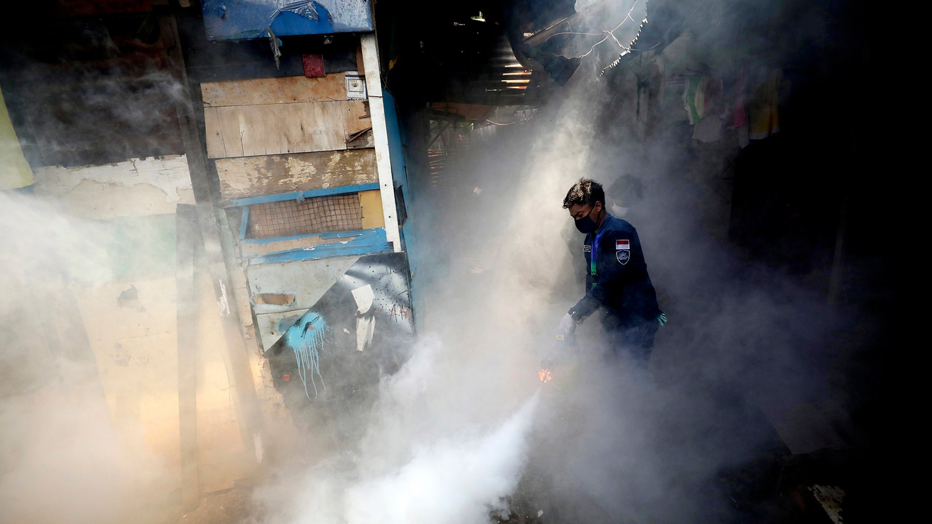 A worker fumigates a slum area to prevent dengue fever outbreak in Jakarta, Indonesia, April 22, 2020.