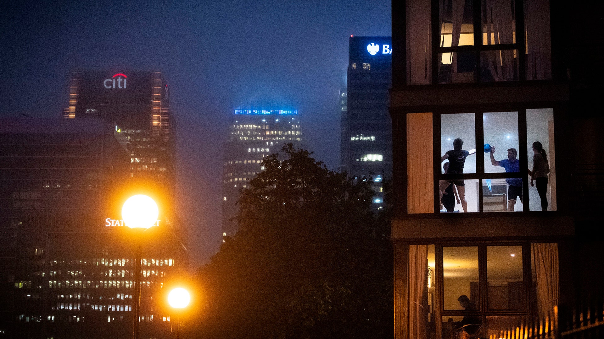 Four people play a makeshift ball game inside an apartment backdropped by city buildings, as the UK continues in lockdown to help curb the spread of the coronavirus in London, April 28, 2020. 