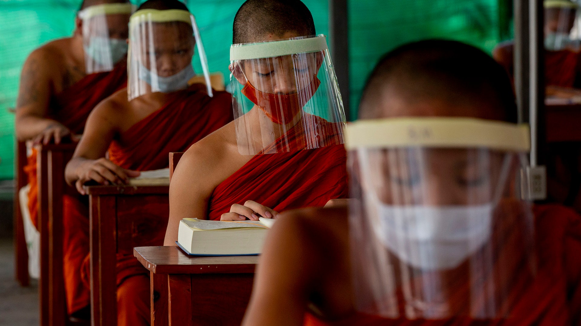 Novice Buddhist monks with protective masks and face shields, seated maintaining social distancing participate in a religious class at Molilokayaram Educational Institute in Bangkok, Thailand, April 15, 2020. 