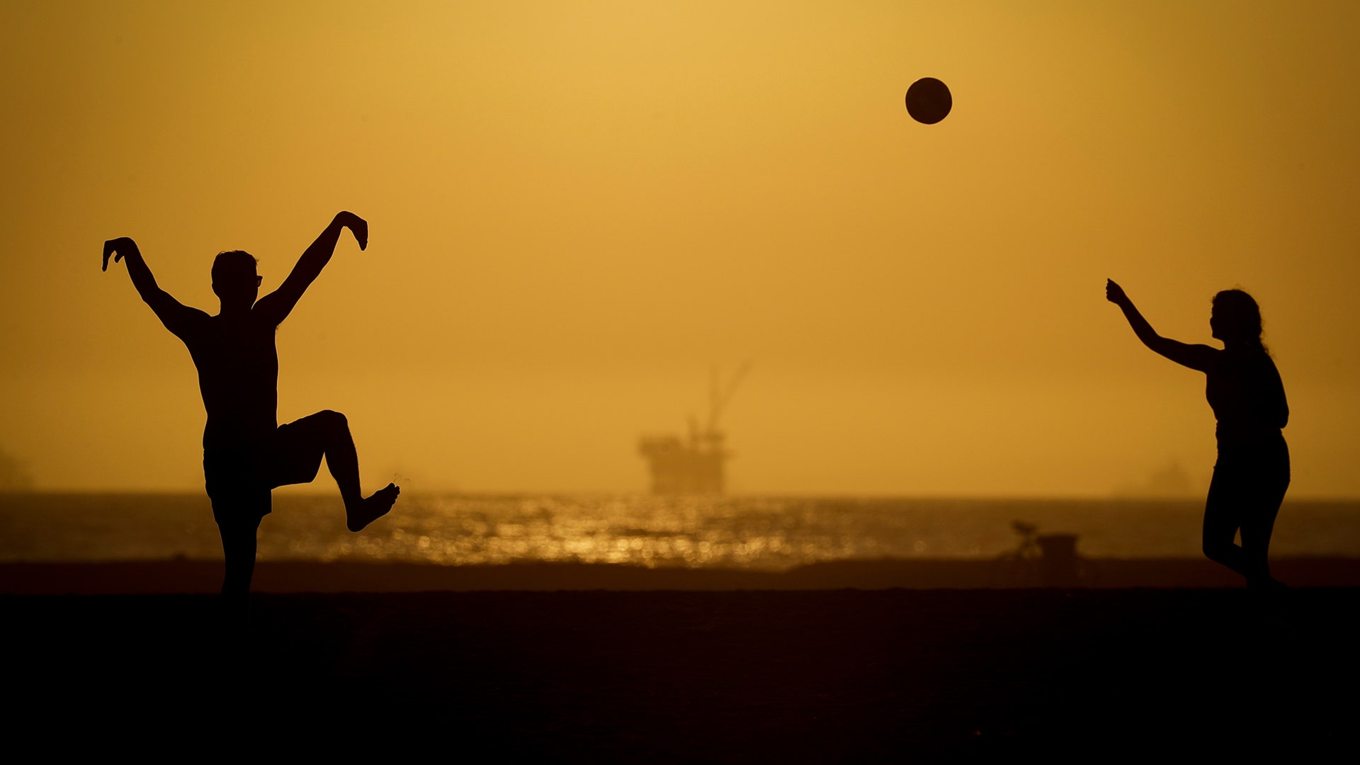A couple plays volleyball on the sand in Huntington Beach, California, April 21, 2020.