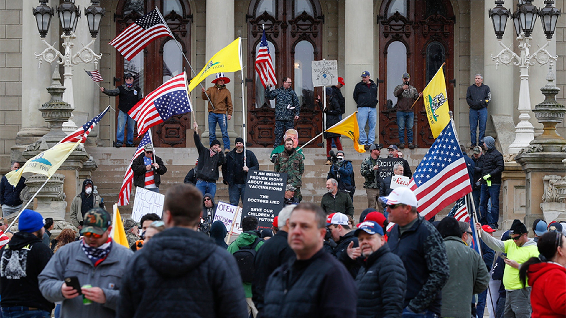 Protesters stand on the steps of the State Capitol in Lansing, Michigan on April 15.