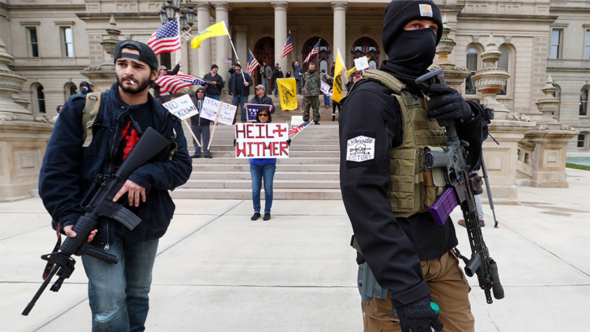 Protesters carry rifles near the steps of the Michigan State Capitol building in Lansing.