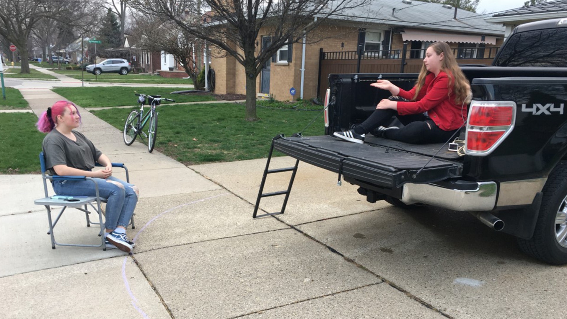 Elizabeth Morgan(right) and Maggie Courser(left) hang out and chat from a supervised distance on a nice day in Dearborn Michigan. Both teenagers taking precautions because their parents are in the medical field at Beaumont hospitals in the Detroit area. Maggie’s mom is a front line nurse tanking care of COVID 19 patients in the ICU and Elizabeth’s mom process and codes incoming virus patients.