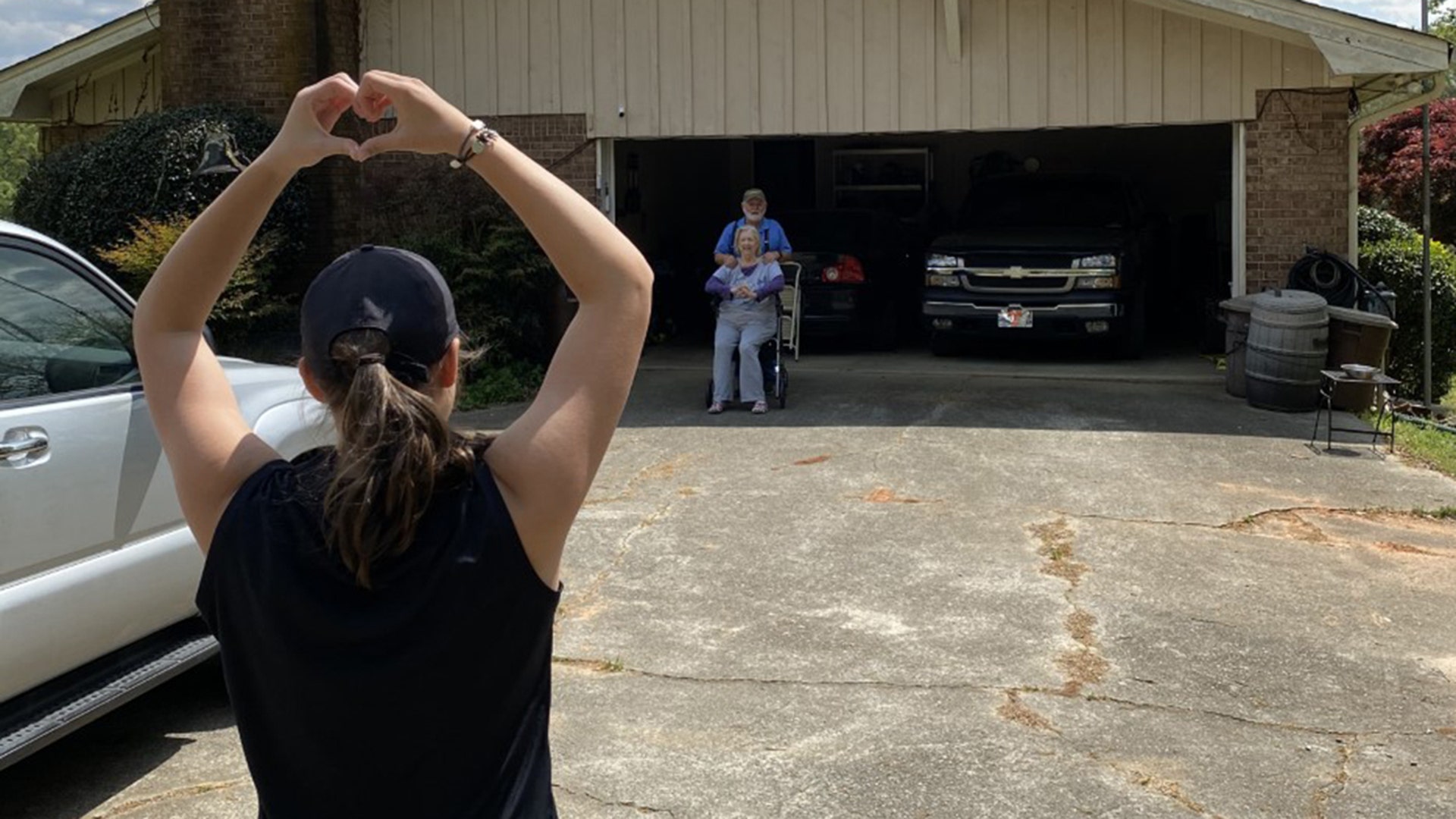 My daughter, Madison Panter, is shown keeping her distance from her grandparents after dropping off a care package of gloves, masks, disinfectant and food. She is giving then a symbol of love as they cry. This is in Powder Springs, Georgia.