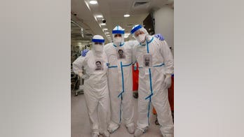 Health workers wear photos of themselves smiling to brighten spirits for coronavirus patients