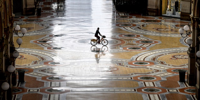 A cyclist rides along an empty Galleria Vittorio Emanuele II shopping arcade following Italy's lockdown due to the COVID-19 emergency, in Milan, Italy, Thursday, April 30, 2020. Italy is in its eighth week of national lockdown, with some partial easing of restrictions on everyday life slated to take effect on Monday, with lifting of yet more limits set for later in coming weeks, on condition the rate of contagion doesn’t sharply start rising again. (Claudio Furlan/LaPresse via AP)