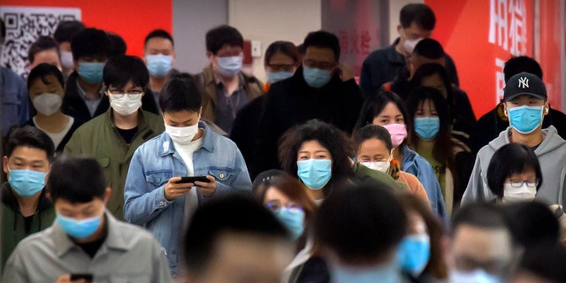 Commuters wear face masks to protect against the spread of new coronavirus as they walk through a subway station in Beijing, Thursday, April 9, 2020. China's National Health Commission on Thursday reported dozens of new COVID-19 cases, including most of which it says are imported infections in recent arrivals from abroad and two "native" cases in the southern province of Guangdong. (AP Photo/Mark Schiefelbein)