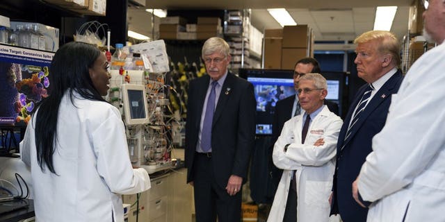 FILE - Dr. Kizzmekia Corbett, left, senior research fellow and scientific lead for coronavirus vaccines and immunopathogenesis team in the Viral Pathogenesis Laboratory, talks with President Donald Trump as he tours the Viral Pathogenesis Laboratory at the National Institutes of Health in Bethesda, Md., last month. (AP Photo/Evan Vucci)