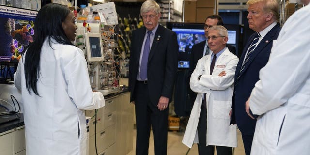 FILE - Dr. Kizzmekia Corbett, left, senior research fellow and scientific lead for coronavirus vaccines and immunopathogenesis team in the Viral Pathogenesis Laboratory, talks with President Donald Trump as he tours the Viral Pathogenesis Laboratory at the National Institutes of Health in Bethesda, Md., last month. (AP Photo/Evan Vucci)