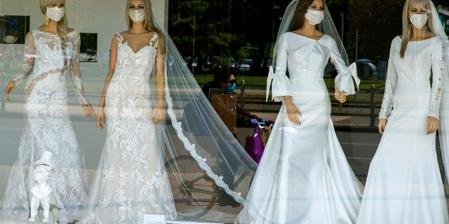 A cyclist wearing a protective mask to protect against coronavirus is reflected in the window of a wedding dress store with mannequins wearing face masks, in Zagreb, Croatia, Thursday, April 23, 2020. The store is closed because of Covid-19 lockdown. (AP Photo/Darko Bandic)