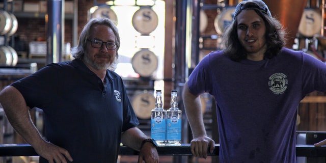 Britt Moon (left), co-owner of Swamp Fox Distilling Co. in Buena Vista, Ga., poses next to a bottle of hand sanitizer made at his distillery (Whisky With A View)