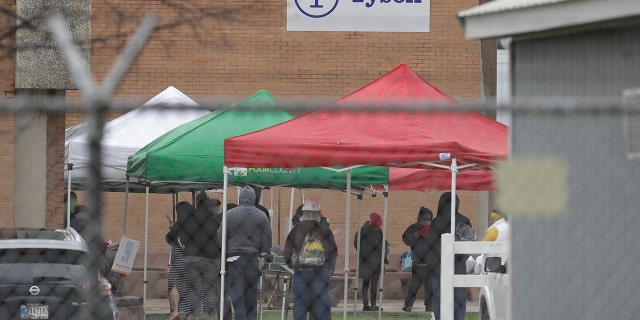 Tyson Fresh Meats plant employees line-up outside of the plant, Thursday, April 23, 2020, in Logansport, Ind. The plant will temporarily close its meatpacking plant in north-central Indiana after several employees tested positive for COVID-19. (AP Photo/Darron Cummings)