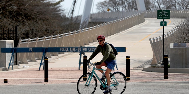 A cyclist, still forbidden to access the Lake Michigan bike trail, passes a police barricade as he takes advantage of a break in cold, damp weather and temperatures reaching the 60s, on Monday in Chicago. (AP)