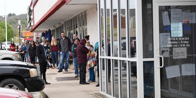 In this Monday, March 30, 2020, photo, a line of around fifty people extends from the door of Arkansas Workforce Center in Fayetteville, Ark. (JT Wampler/The Northwest Arkansas Democrat-Gazette via AP)