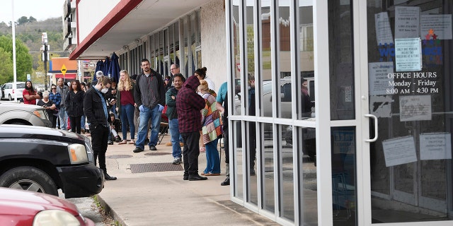 In this Monday, March 30, 2020, photo, a line of around fifty people extends from the door of Arkansas Workforce Center in Fayetteville, Ark. (JT Wampler/The Northwest Arkansas Democrat-Gazette via AP)