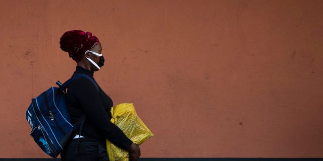 A woman, wearing a protective mask as a precaution against the spread of the new coronavirus, carries her shopping as she walks on the street in Johannesburg, South Africa.