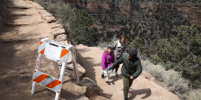 In this March 27, 2020 photo, Shelly Clayton, center, walks up the Bright Angel Trail at Grand Canyon National Park, Ariz., with her children Audrey Kuhar, 11, left, and Cooper Kuhar, 11. (Jake Bacon/Arizona Daily Sun via AP)