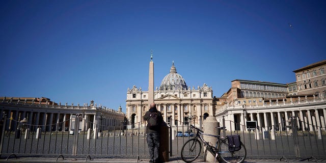 A man stands in front of St. Peter's Square and Basilica during Pope Francis' weekly general audience, streamed by the Vatican television due to restrictions to contain the Covid-19 virus, at the Vatican, Wednesday, April 1, 2020. (Associated Press)