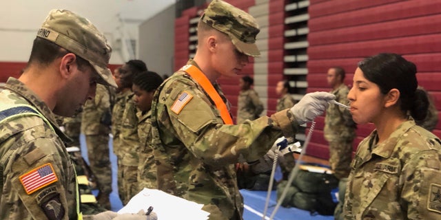 Recent Army basic combat training graduates have their temperatures taken.