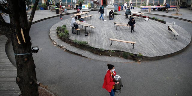 A volunteer carries a tea distribution machine in the "Aurore" center for homeless and migrants in Paris, Thursday, April 2, 2020.