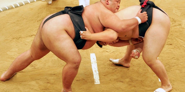 Sumo wrestler Takayuki Ichihara from Japan, left, fights against compatriot Keisho Shimoda in the heavyweight final of the Sumo tournament at the World Games in Duisburg, Germany in 2005. A Japanese sumo wrestler has tested positive for the coronavirus, further threatening postponement of next month’s Summer Grand Sumo Tournament which has already been delayed. (AP Photo/Martin Meissner, FIle)