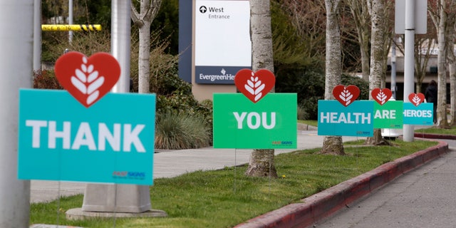 A line of signs in appreciation of health care workers working during the coronavirus outbreak line the curb in front of EvergreenHealth Medical Center Thursday, April 2, 2020, in Kirkland, Wash. An emergency room doctor in Seattle, Wash., who works at the hospital was in critical condition last month after being diagnosed with COVID-19, He described his "scary" journey to recovery on Monday. (AP Photo/Elaine Thompson)