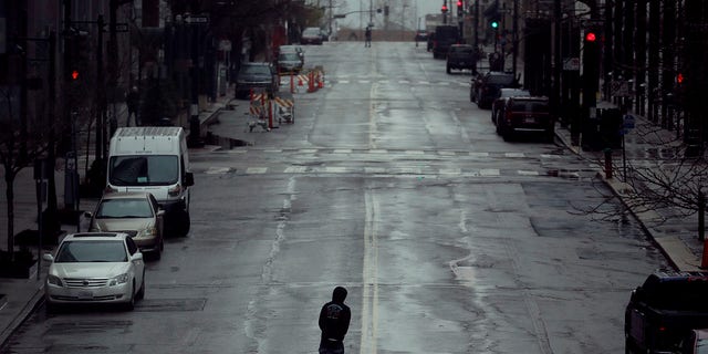 A man crosses an empty street Friday, April 3, 2020 in downtown Kansas City, Mo. The city is under a stay-at-home order, asking everyone to stay inside and away from others as much as possible, in an effort to slow the spread of the new coronavirus. (Associated Press)